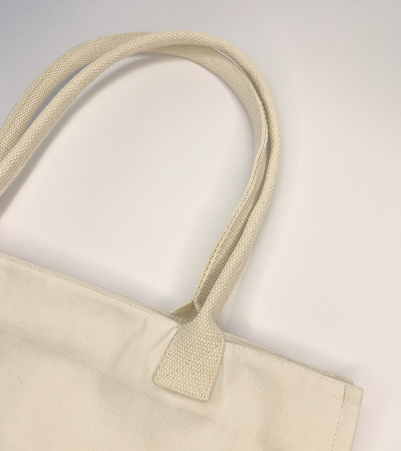 Close-up of a beige tote bag with handle on a plain background
