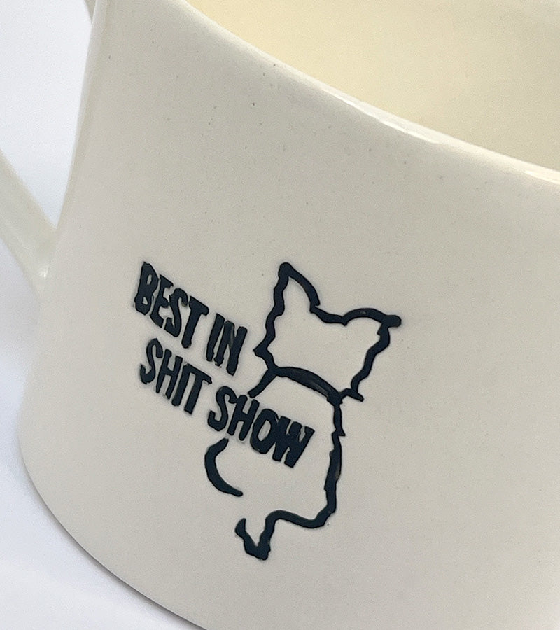 White mug with black 'Best in shit show' text and dog illustration on a white background