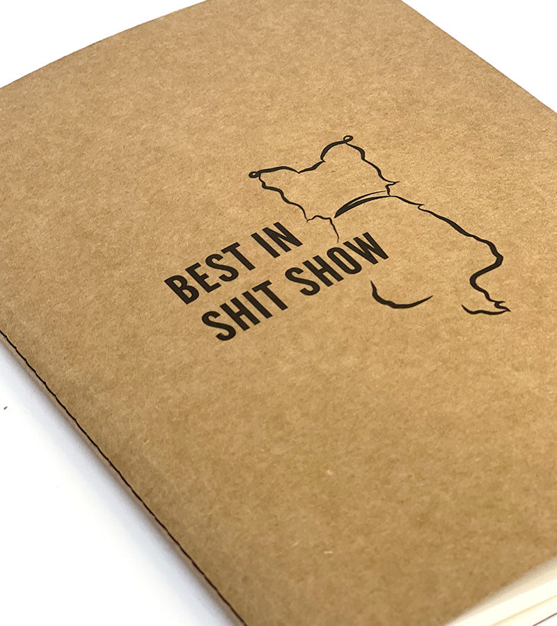 Brown notebook with 'Best in Shit Show' text and a dog illustration on a white background