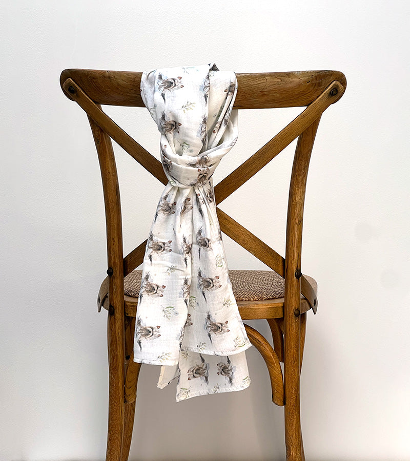 White scarf with Yorkie dog pattern draped over a wooden chair against a white background
