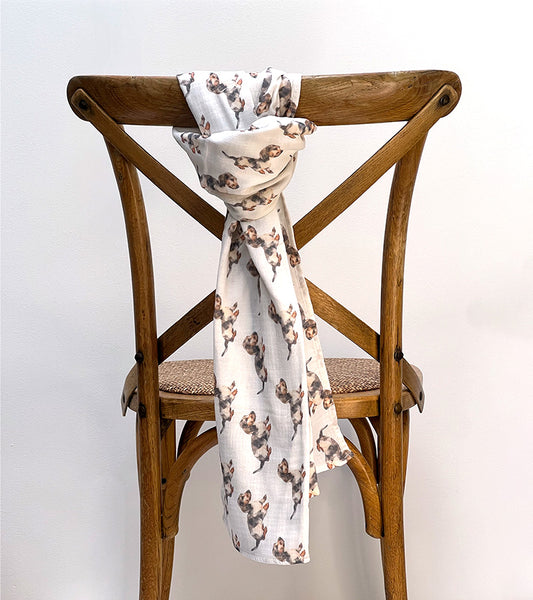 Dachshund dog-patterned scarf draped over a wooden chair against a white background