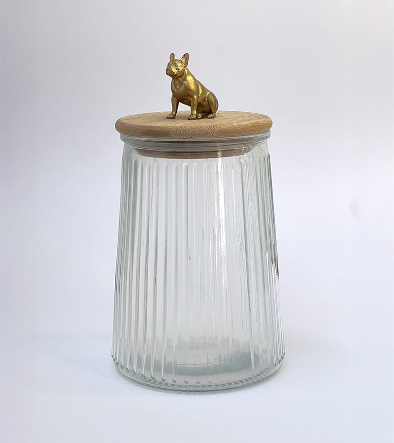 Clear glass jar with a wooden lid and gold bulldog figurine on a white background