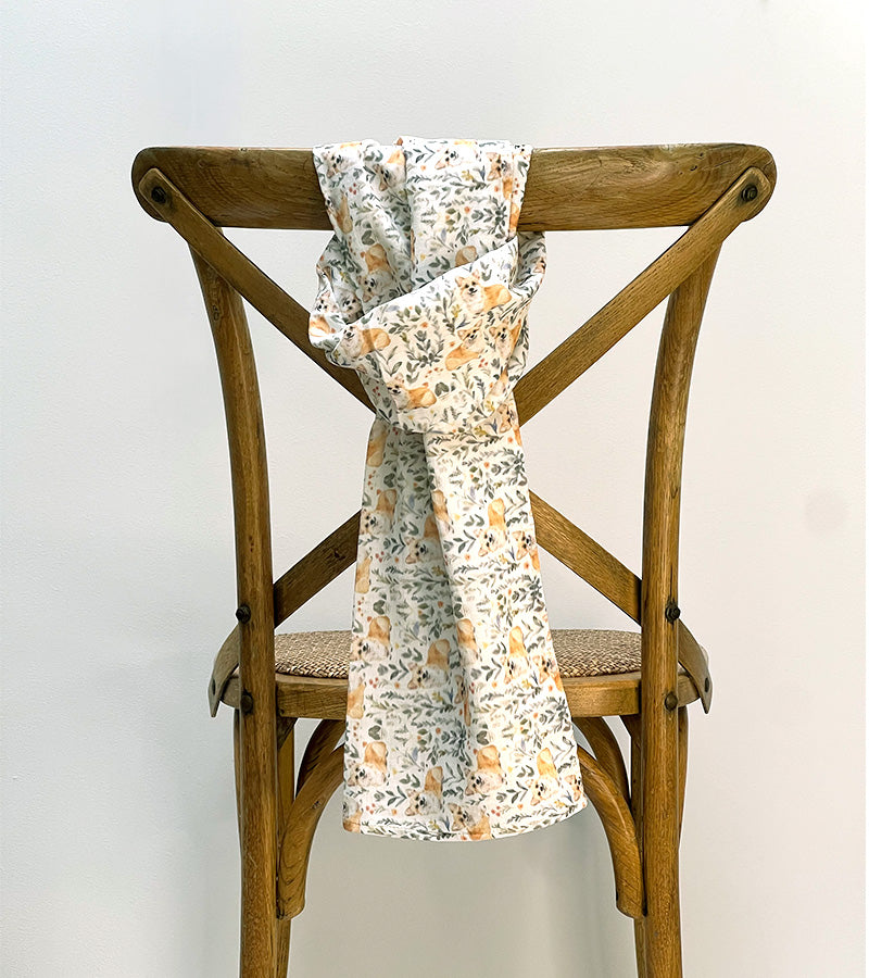 Floral-patterned scarf draped over a wooden chair against a white background