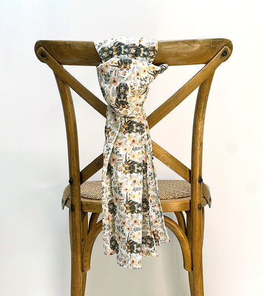 Floral and dog pattern scarf draped over a wooden chair against a white background