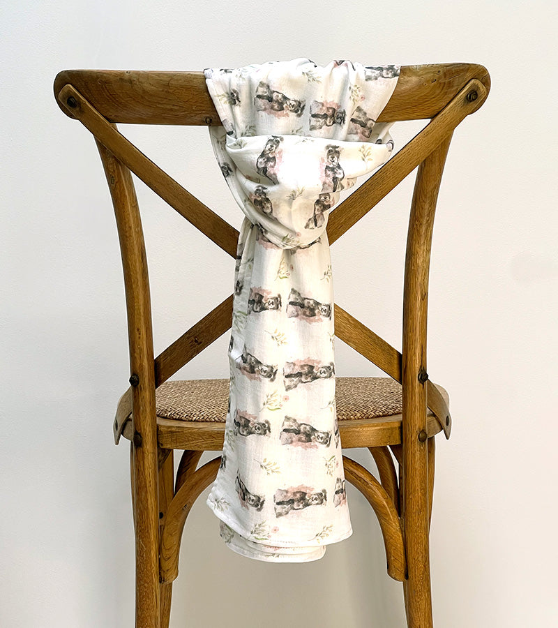 Scarf with dog pattern draped over a wooden chair against a white background