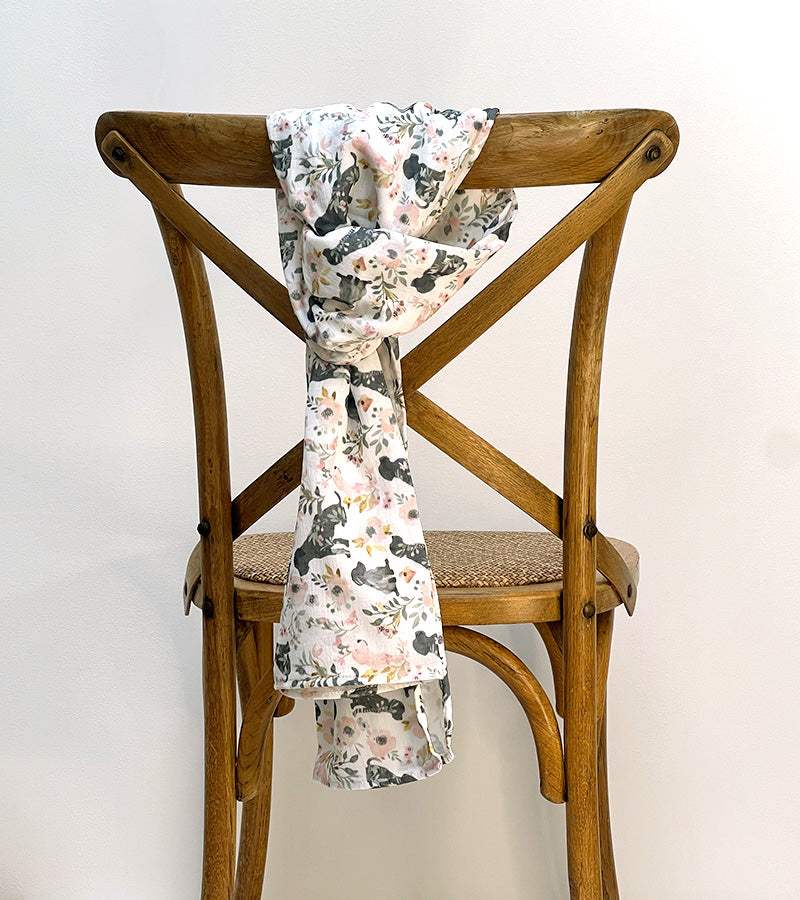 Floral patterned scarf draped over a wooden chair against a white background