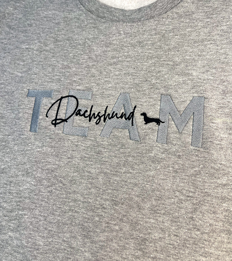 Gray sweatshirt with 'TEAM Dachshund' text and dog silhouette image on a plain background