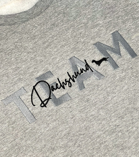 Gray sweatshirt with 'TEAM Dachshund' text and dog silhouette image on a plain background