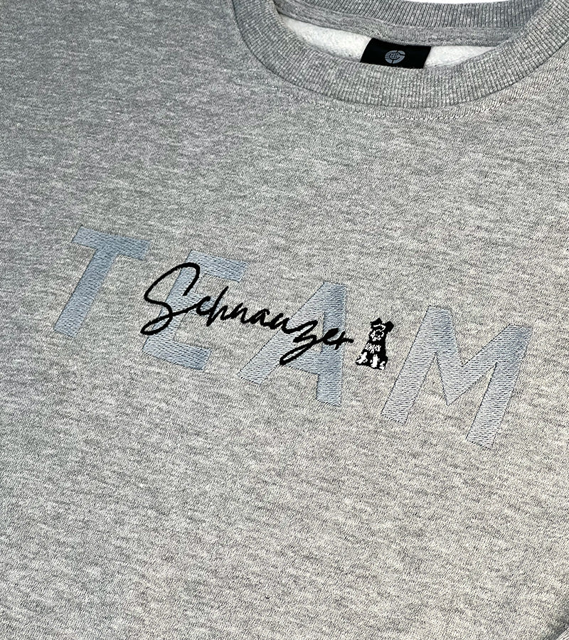 Gray sweatshirt with 'Team Schnauzer' text and logo on a plain background