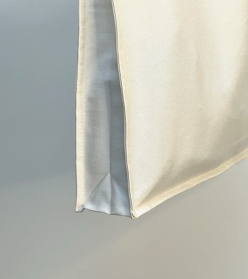 Close-up of a beige tote bag corner on a plain background