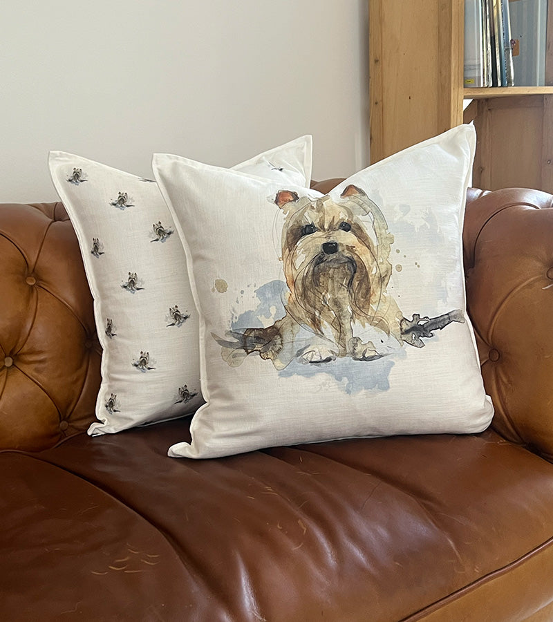 Decorative pillows with a Yorkie dog design on a brown leather couch.
